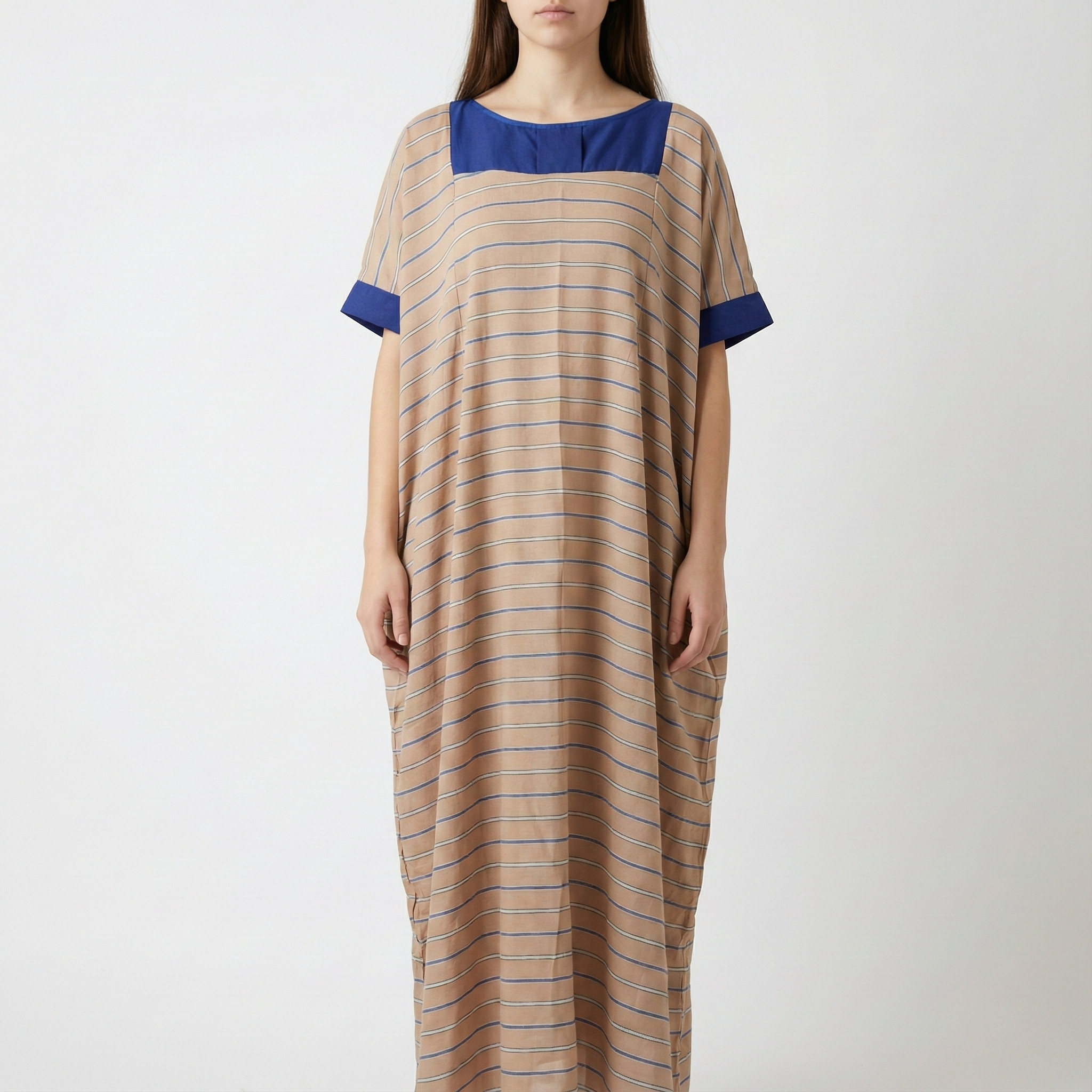 Manta Wayuu de color beige con rayas horizontales azules, cuello cuadrado y detalles en azul sólido en mangas y pecho.