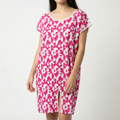 Manta Wayuu corta de color fucsia y blanco con estampado geométrico, detalles de encaje blanco en cuello y mangas, y abertura frontal inferior.