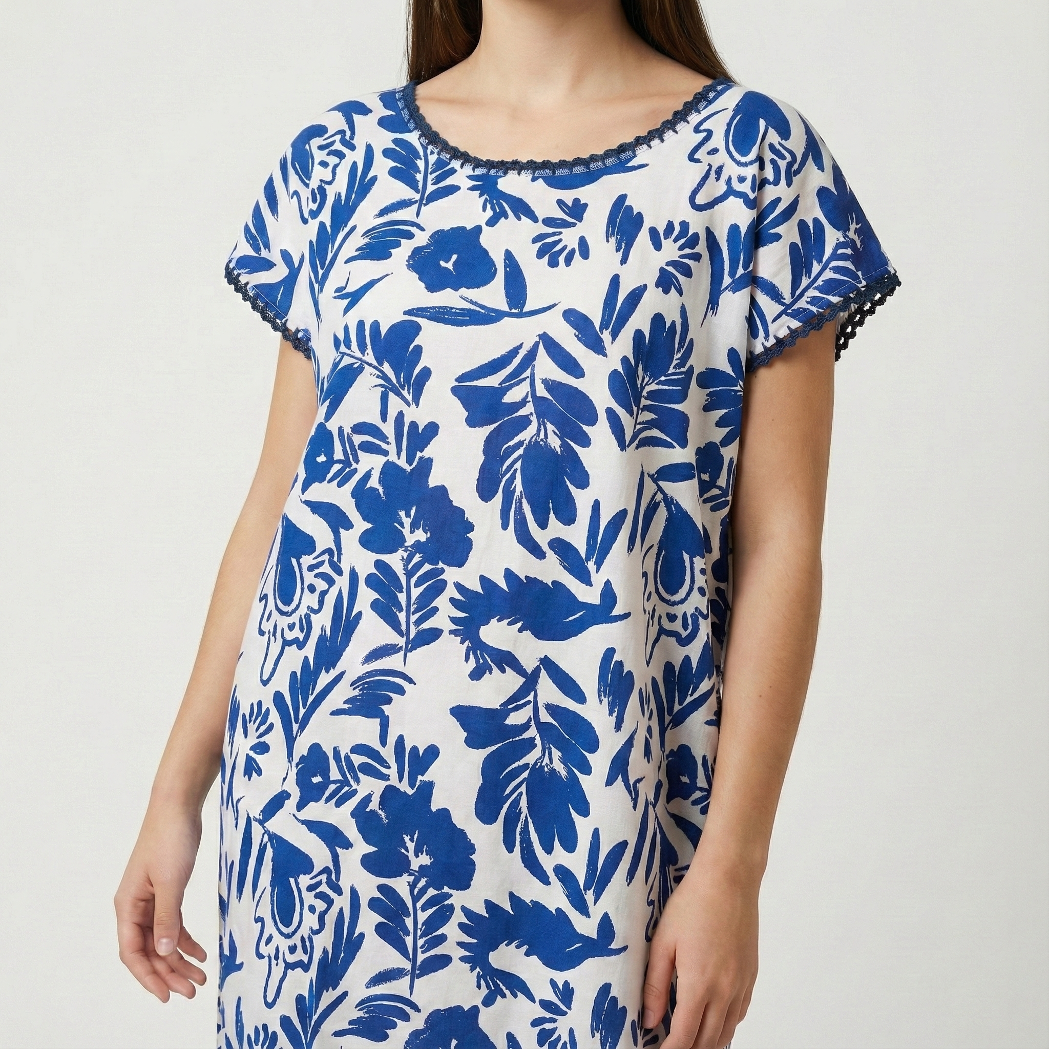 Manta Wayuu moderna de lino blanco con estampado botánico azul cobalto y detalles de encaje en el cuello.