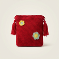 Mini bandolera artesanal color rojo con detalles de flores tejidas y borlas laterales, diseño ligero y elegante.