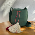 Mochila Wayúu artesanal en color verde bosque con borlas grandes contrastantes y cordón trenzado.
